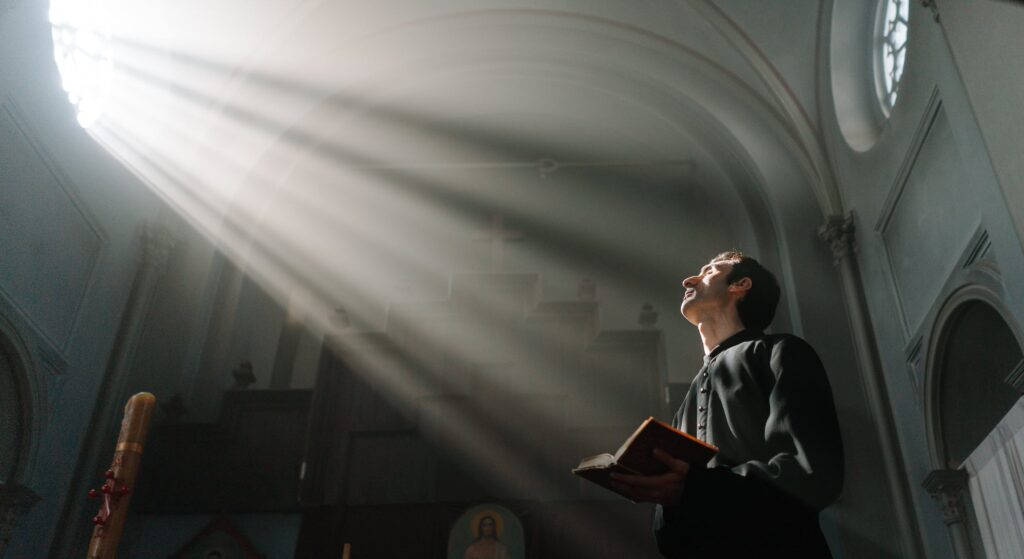 Photo by cottonbro studio: https://www.pexels.com/photo/sunrays-passing-through-a-church-window-beside-a-priest-holding-a-bible-9589499/